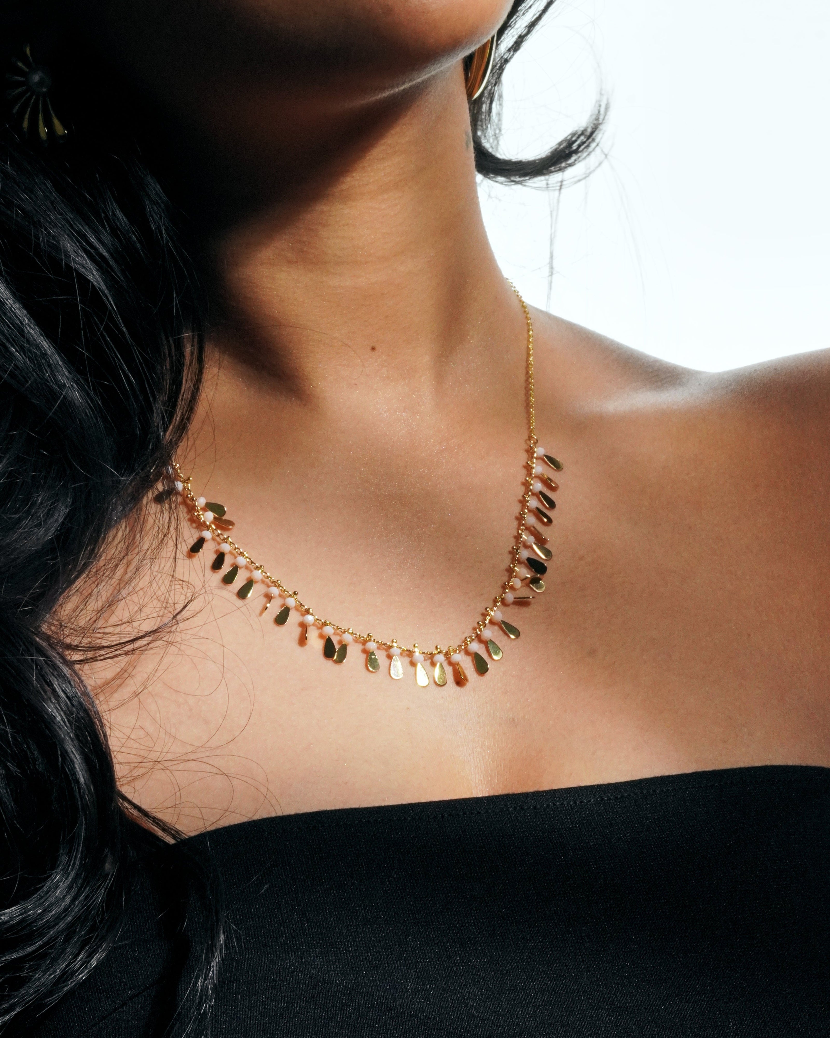 Close-up of a woman wearing a gold necklace with a blurred background