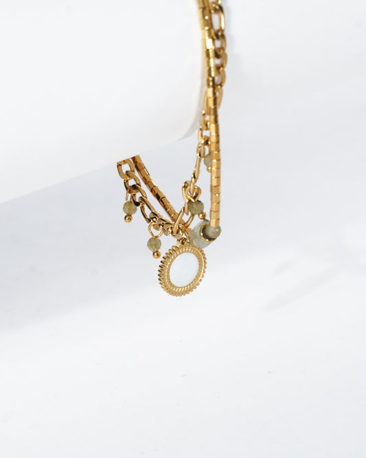 Gold bracelet with circular charms on a white background