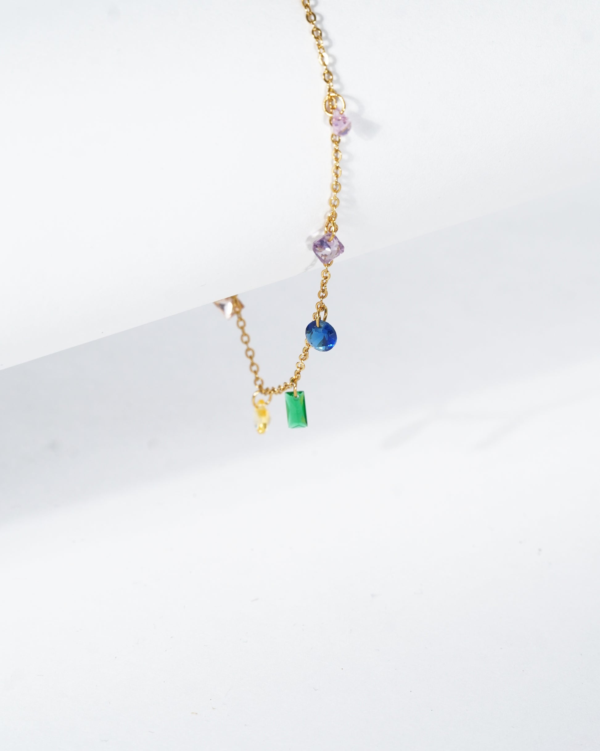 Gold necklace with colorful beads on a white background