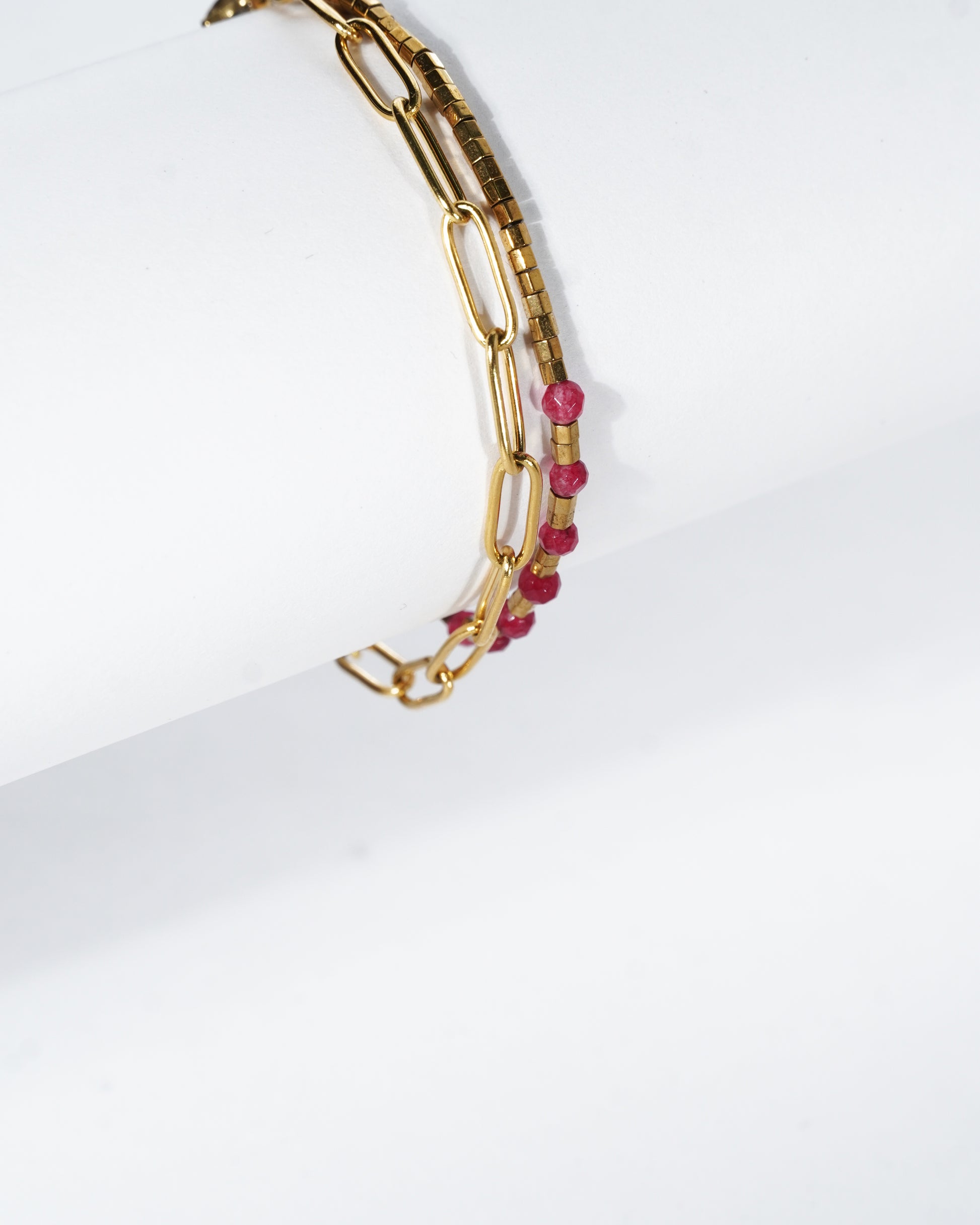 Gold chain bracelet with pink beads on a white background