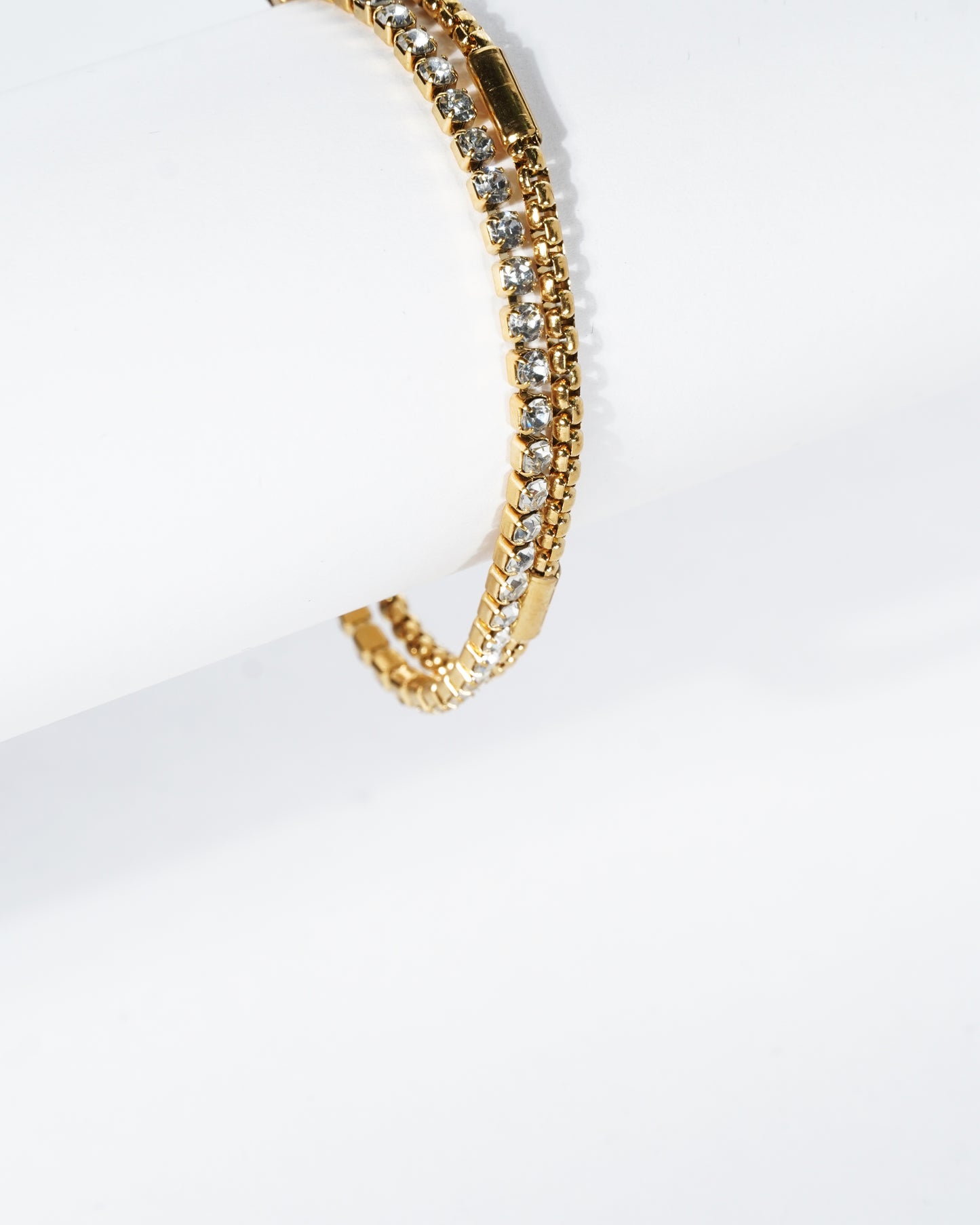 Gold bracelet with clear stones on a white background