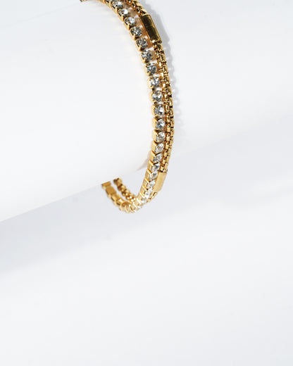 Gold bracelet with clear stones on a white background