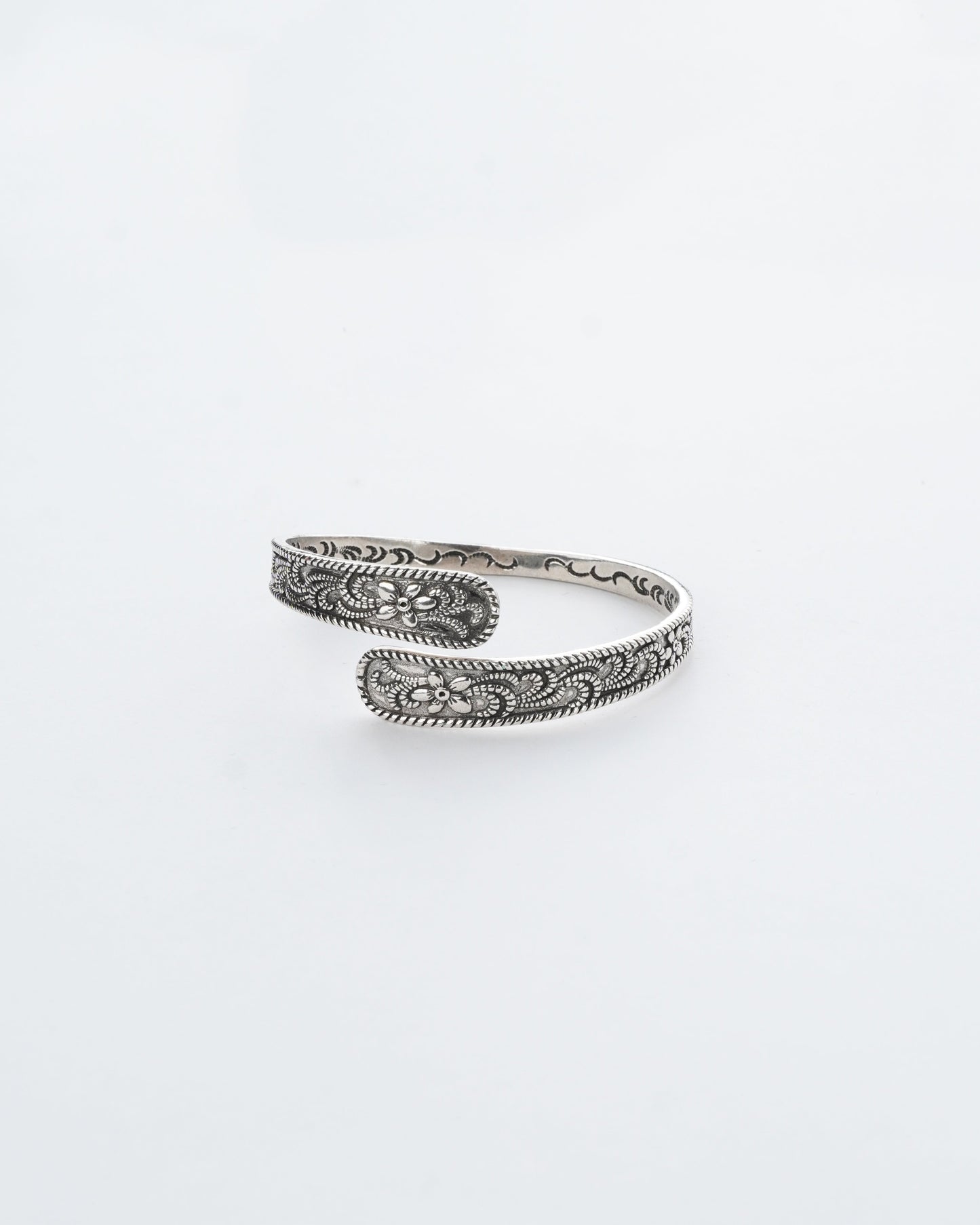 Silver bracelet with intricate patterns on a white background