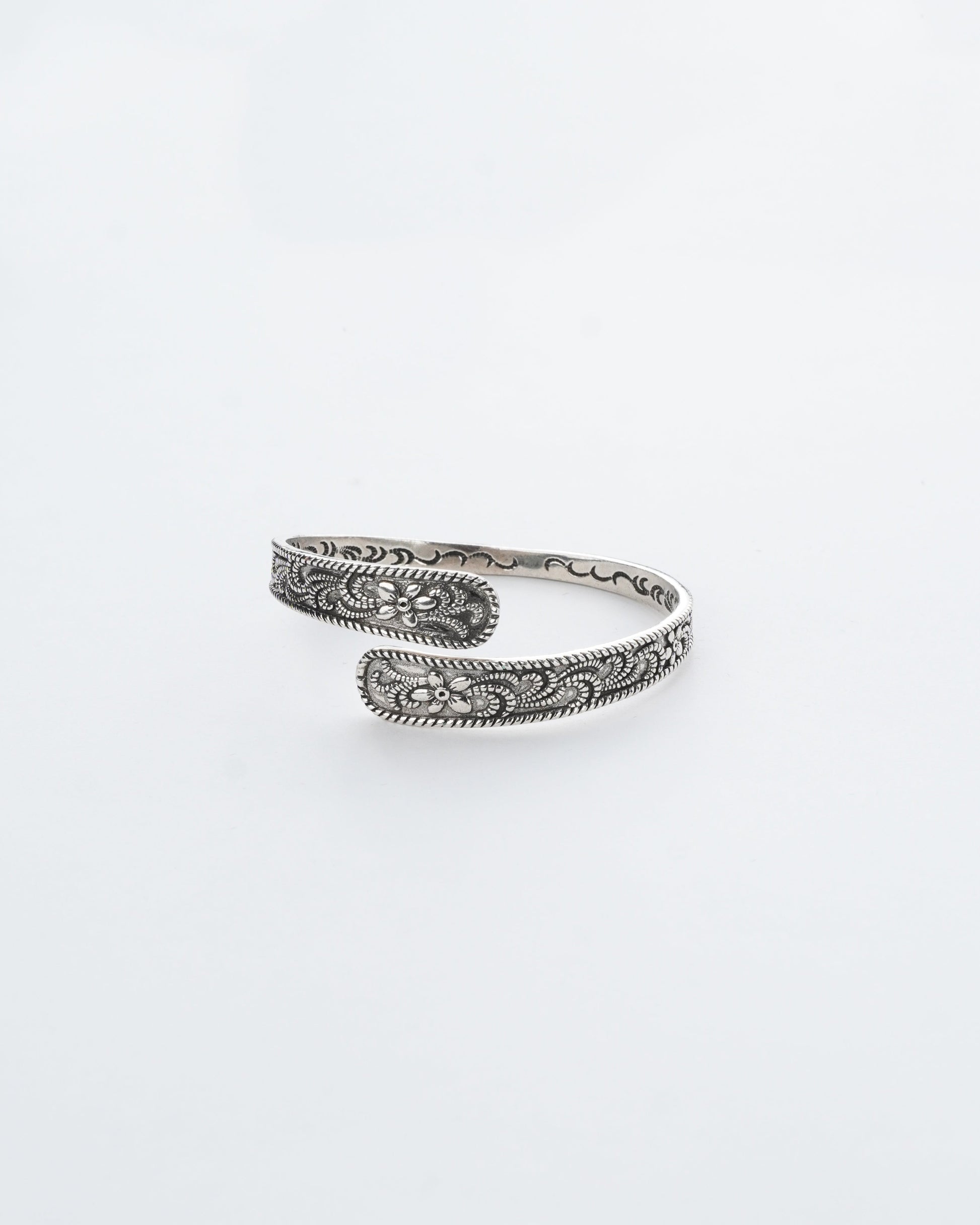 Silver bracelet with intricate patterns on a white background