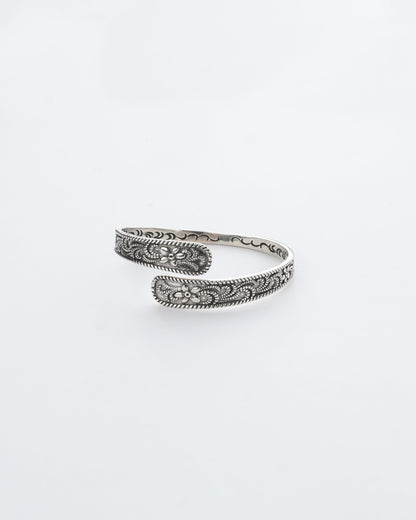 Silver bracelet with intricate patterns on a white background