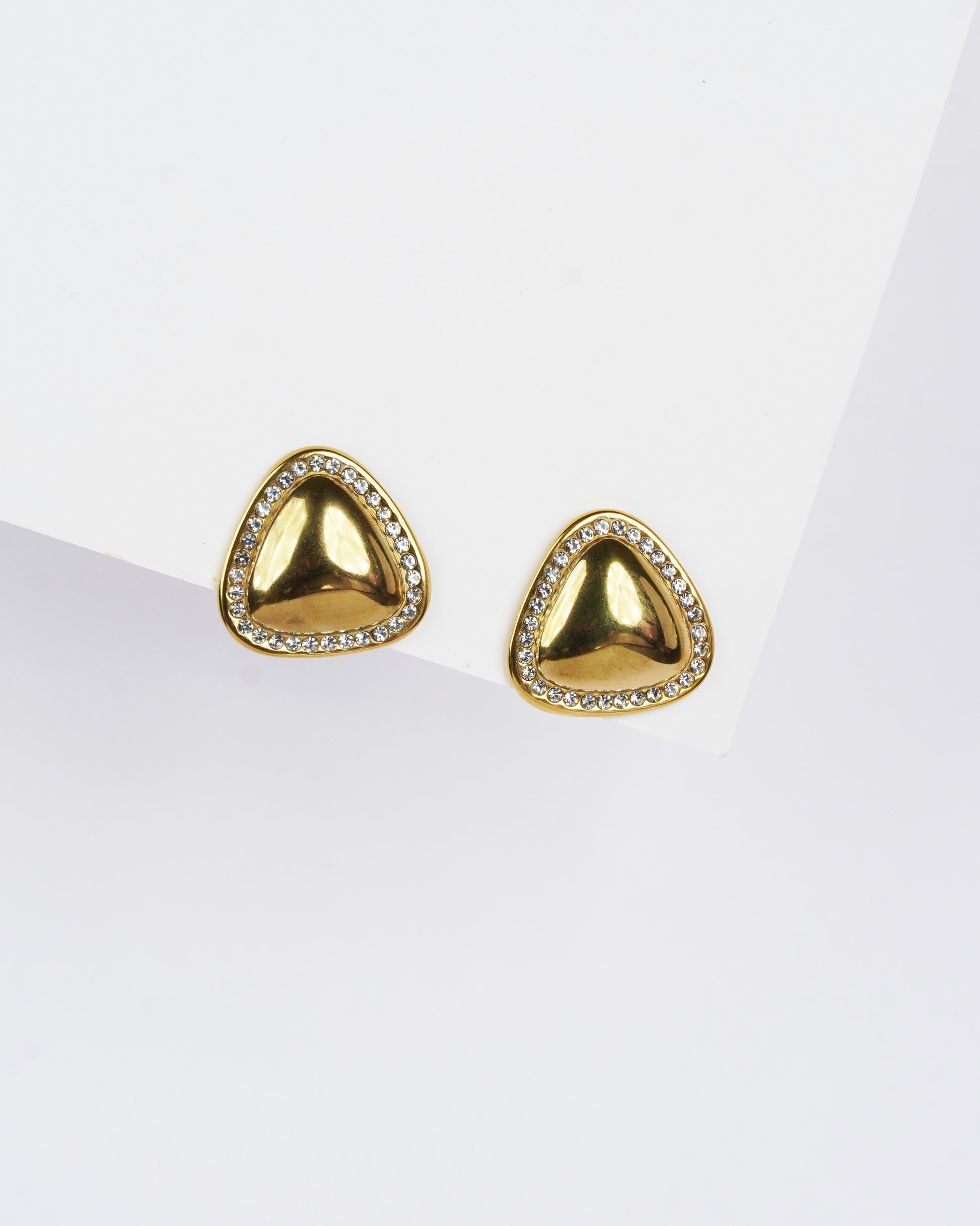 Gold triangle-shaped earrings with clear stones on a white background